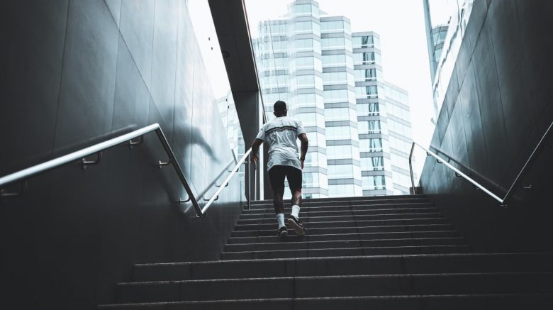 A person climbs outdoor stairs in Perth, against a modern city backdrop.